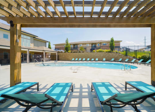 lounge chairs under a pergola overlooking a resort-style pool