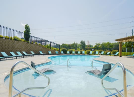 a resort-style pool with two lounge chairs in the  shallow wading are of the water