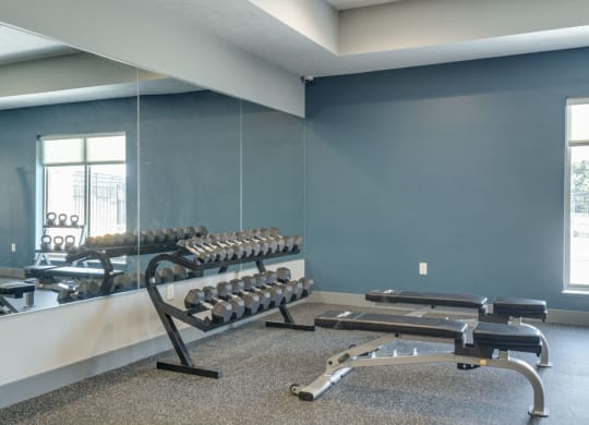 Free weights and benches in the 24 hour fitness center at The Villas at Mahoney Park