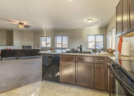 A kitchen with a black fridge and brown cabinets.