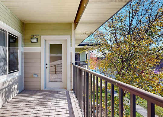 a balcony overlooking a pond with a window to the bedroom and a door to the living room