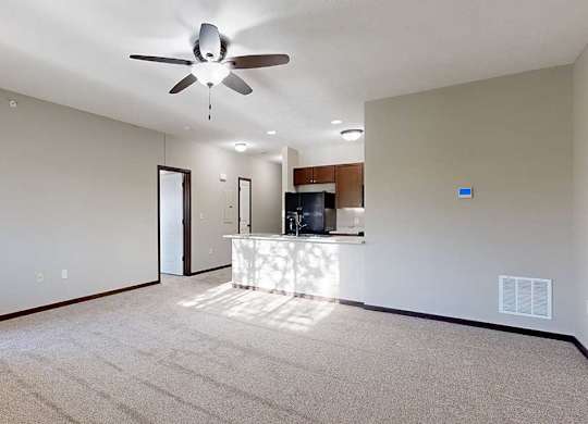 an open-concept living room and kitchen with a ceiling fan