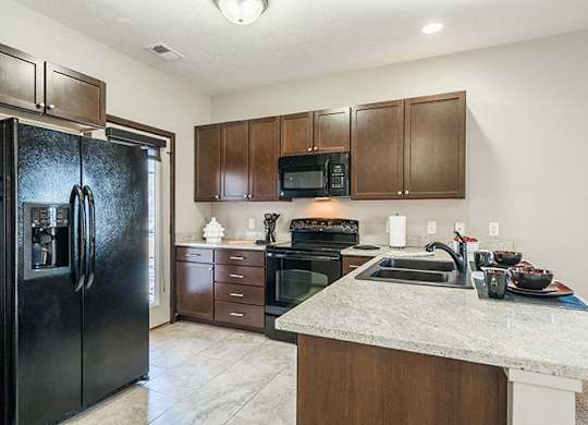 Kitchens feature dark cabinets, sleek black appliances, and gorgeous granite counter tops.