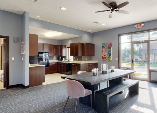 a dining area in the clubhouse with a table and chairs and a kitchen in the background