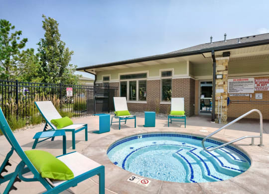 Round hot tub with step walk-in and turquoise lounge chairs around it