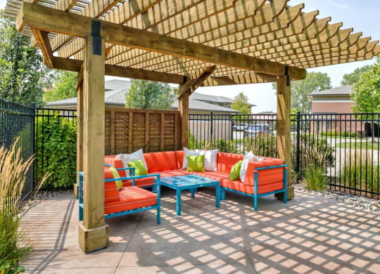 Wood pergola area with bright orange and turquoise lounge furniture positioned under it