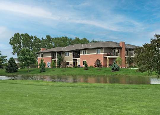 An apartment building with a pond in front of it