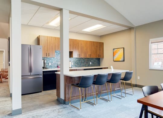 Community clubhouse kitchen with refrigerator and island seating for resident use in the clubhouse at The Northbrook Apartments