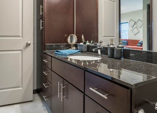 A bathroom with a sink, mirror, and cabinets.