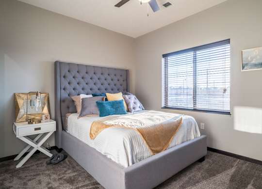 A bedroom with a large bed and a window with blinds.