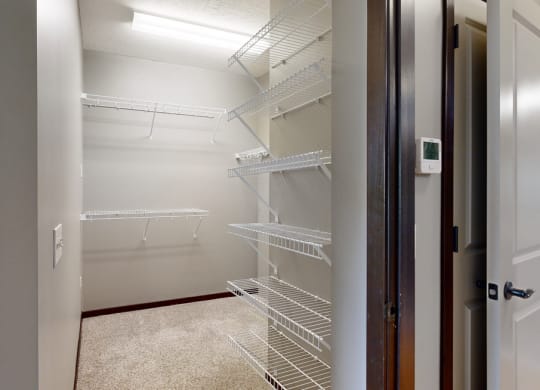 a walk-in closet in the bedroom with lots of shelves