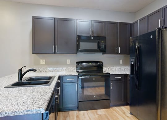 a kitchen with dark cabinets and granite countertops
