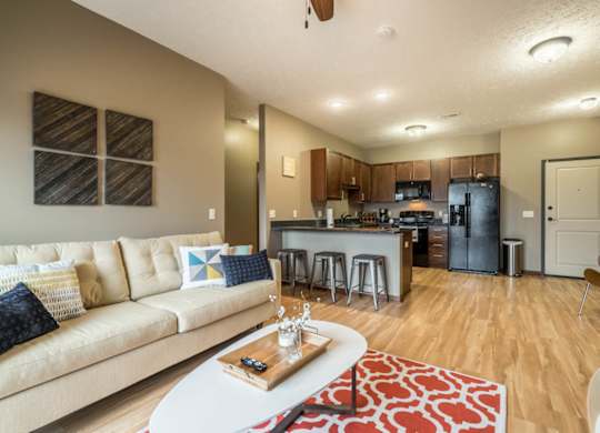 A modern living room with a kitchen in the background.