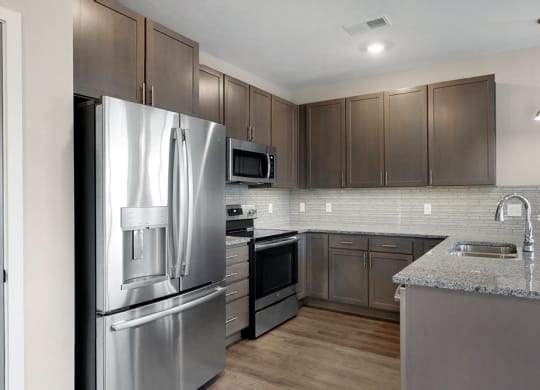 This 2 bedroom Marigold with den floor plan at WH Flats features a tile backsplash (available in some homes), stainless steel appliances, granite countertops and large peninsula.