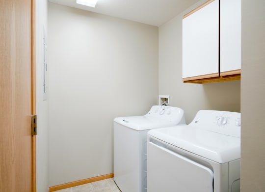 the laundry room has a washer and dryer and cabinet for storage