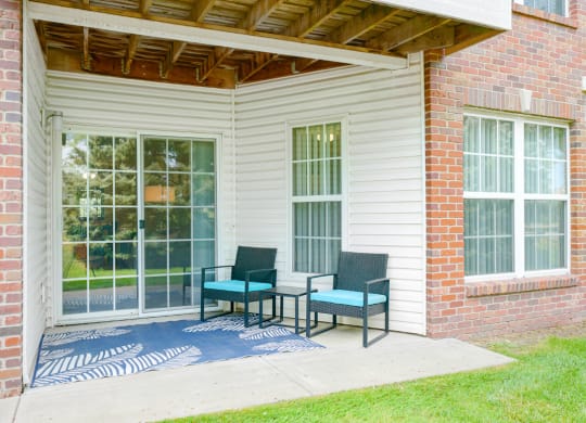 Back patio with two chairs and a rug in front of sliding glass door