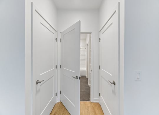 A hallway with white doors and a wooden floor.