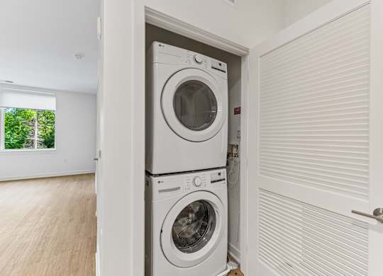 A white washing machine is in a white laundry room.