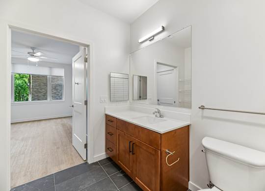 A white bathroom with a wooden vanity and a white tub.