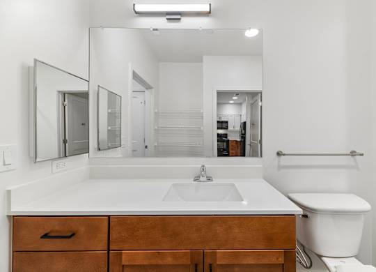A white bathroom with a sink, toilet, and mirror.
