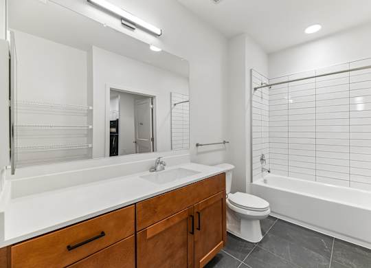 A white bathroom with a wooden vanity and a white bathtub.