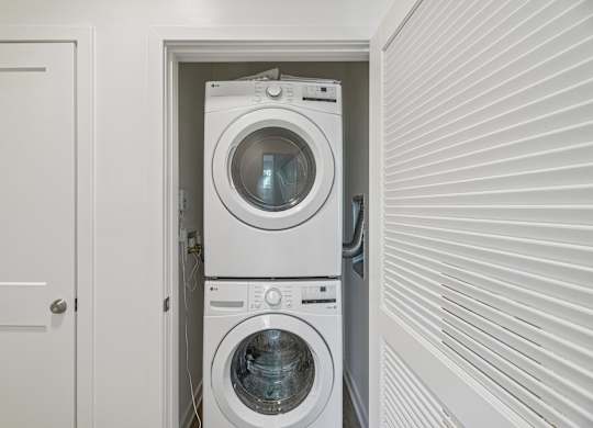 A white door is open to a small laundry room with a washer and dryer.