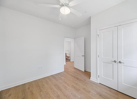 A room with a ceiling fan and white walls.
