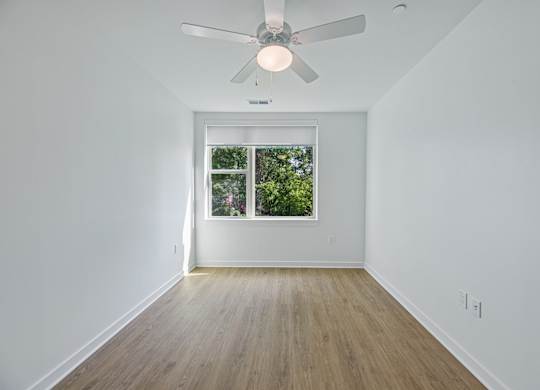 A room with a ceiling fan and a window.