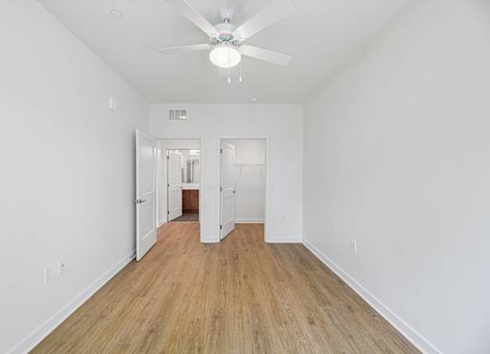 A room with a ceiling fan and wooden flooring.