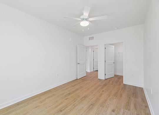 A room with a ceiling fan and wooden floors.