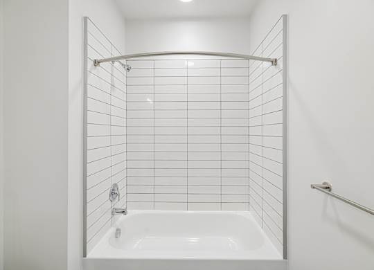 A white bathroom with a white tub and white tiles.