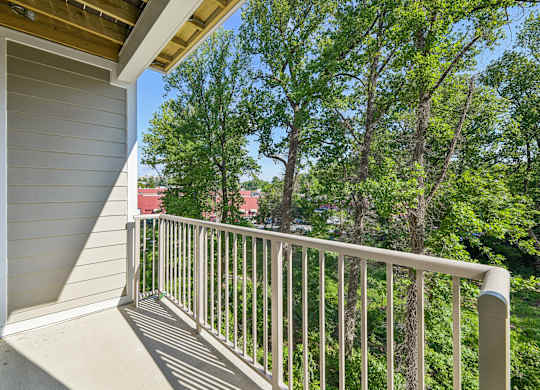 A balcony with a white railing overlooks a green tree.