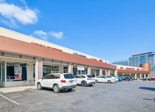 A row of cars are parked in front of a HomeGoods store.