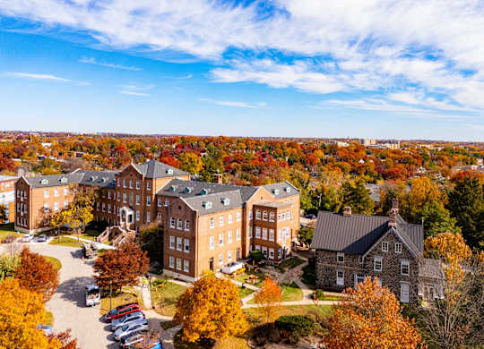 A large building complex surrounded by trees with autumn leaves.