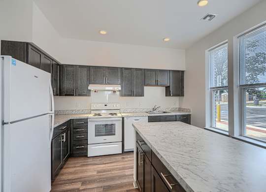 A kitchen with a white refrigerator and black cabinets.