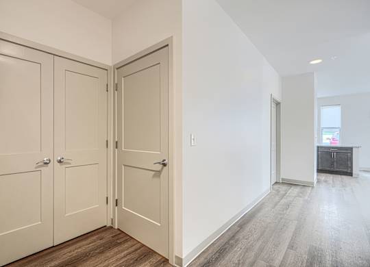 A room with a white wall and a wooden floor with a white door.