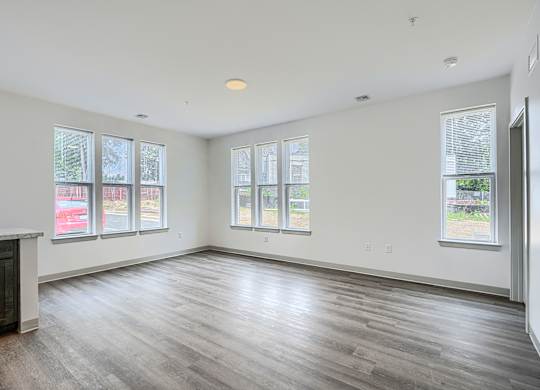 A large empty room with wooden floors and windows.