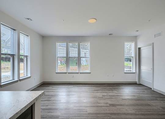 A large empty room with a kitchen island and windows.
