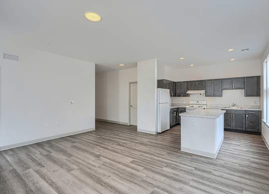 A kitchen with a white fridge and wooden floors.