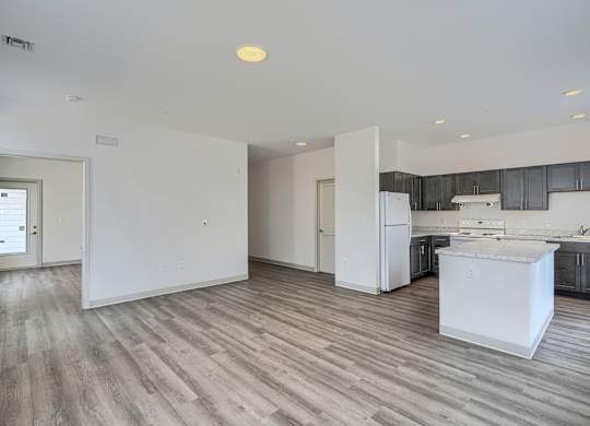 A kitchen with a white fridge and wooden floors.