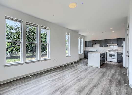 A spacious kitchen and living room with hardwood floors and large windows.