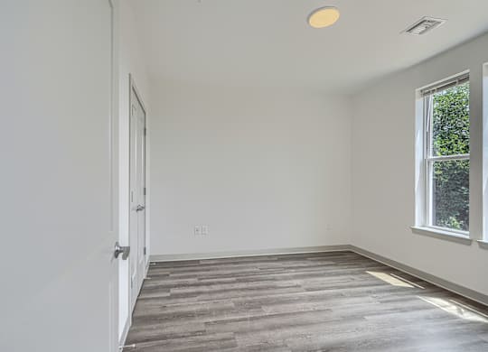 A room with a wooden floor and a window on the right side.