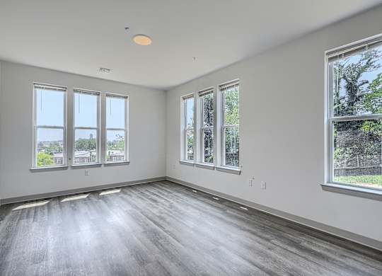 A large empty room with wooden floors and windows.