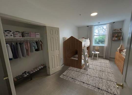 A baby's room with a crib, a changing table, and a closet with baby clothes.