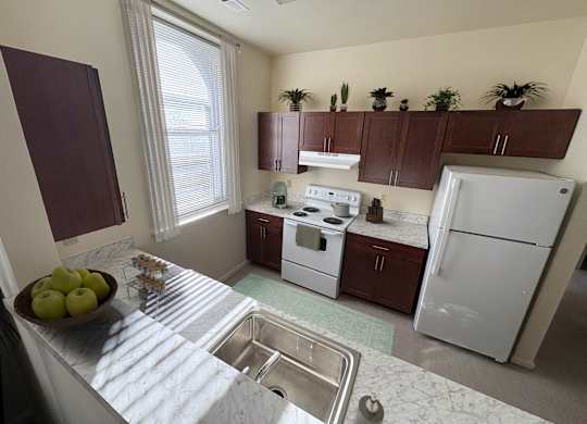 A kitchen with a white fridge and a bowl of apples on the counter.