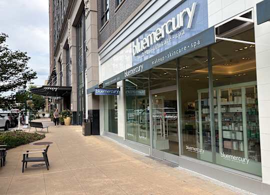 A Blumercury storefront with a bench outside.
