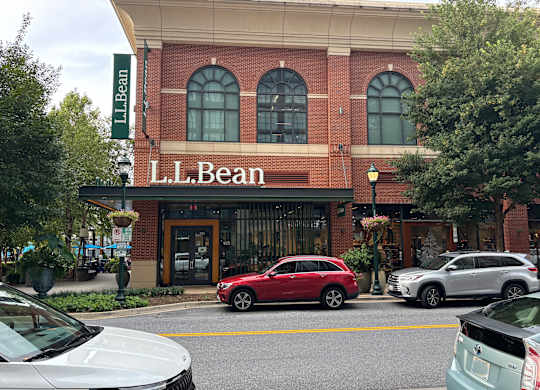 A red car is parked in front of the L.L. Bean store.