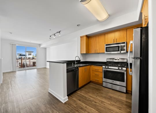 a kitchen with black counter tops and stainless steel appliances and wood floors