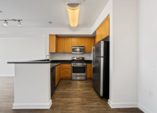 an empty apartment kitchen with black countertops and stainless steel appliances