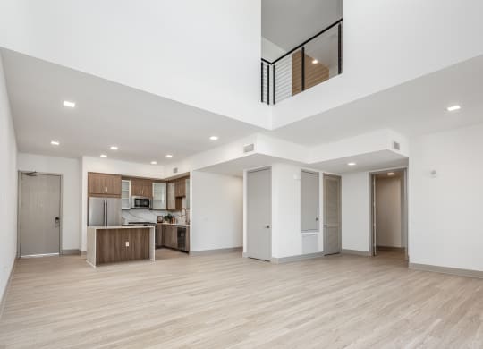 a renovated living room and kitchen with white walls and wood floors